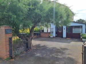 a house with a tree in front of a fence at Room at Lindley in Ludlow