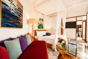 a bedroom with a bed and a couch at River Song Ubud, Bali in Ubud