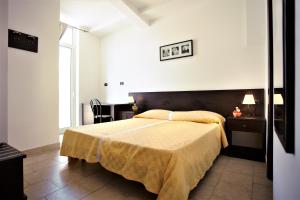 a bedroom with a large bed with a yellow blanket at Hotel Marabel in SantʼAlessio Siculo