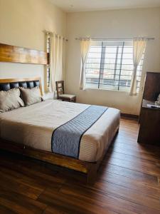 a bedroom with a large bed and a large window at Srj's Thaneesh Residency in Ooty +5 photos