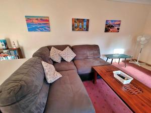 a living room with a brown leather couch and a wooden table at Kates Cottage in Aireys Inlet