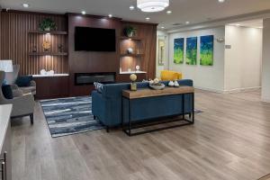 a living room with a blue couch and a tv at Comfort Inn & Suites Concord - Kannapolis in Concord