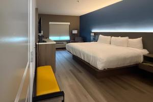 a bedroom with a white bed and a yellow bench at Comfort Inn & Suites Concord - Kannapolis in Concord