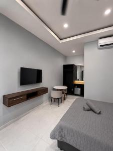 a bedroom with a bed and a tv on a wall at Chenang Private Pool Villa & Cottage in Pantai Cenang