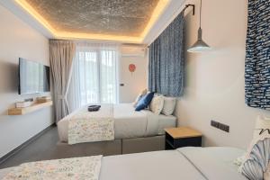 a hotel room with two beds and a tv at Ozonizia Family Suites Mai Khao Phuket Yacht Haven in Phuket