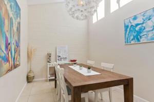 a dining room with a wooden table and white chairs at Beachside Villa in Apollo Bay