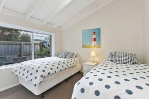 two beds in a bedroom with a lighthouse on the window at Beachside Villa in Apollo Bay