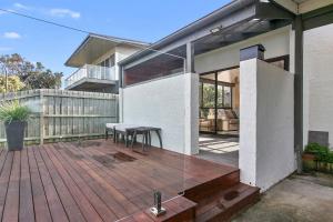 a house with a wooden deck with a table on it at Beachside Villa in Apollo Bay +8 photos