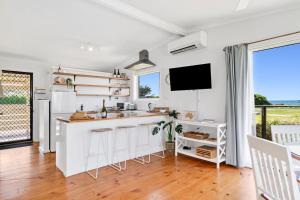 a white kitchen with a counter and a tv at Beachfront Apartment at Apollo in Apollo Bay