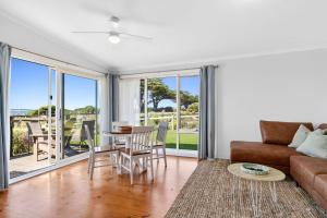 a living room with a couch and a table and chairs at Beachfront Apartment at Apollo in Apollo Bay