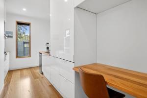 a kitchen with white cabinets and a wooden table at Bimbadeen Bliss in Aireys Inlet