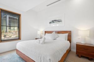 a bedroom with a bed with white sheets and a window at Bimbadeen Bliss in Aireys Inlet