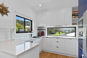 a white kitchen with white cabinets and a window at Casino Views in Apollo Bay