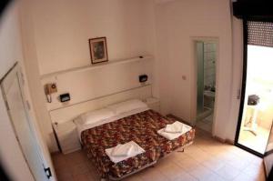 a small bedroom with a bed and a mirror at Hotel Sacramora in Rimini