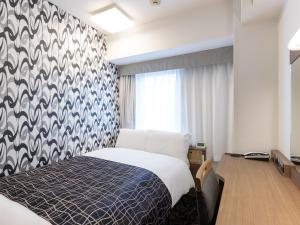 a bedroom with a bed with a blue and white patterned wall at APA Hotel Osaka Higobashi Ekimae , All Rooms Non-Smoking in Osaka