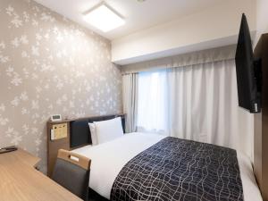 a hotel room with a bed and a television at APA Hotel Osaka Higobashi Ekimae , All Rooms Non-Smoking in Osaka