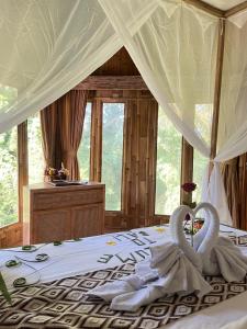 two swans are sitting on a bed in a bedroom at Poka Ubud Hidden Paradise & Spa by EPS in Ubud +245 photos