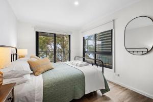 a white bedroom with a bed and a window at Omaroo in Wye River