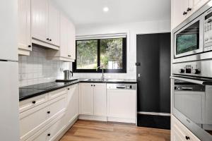 a white kitchen with a sink and a window at Omaroo in Wye River