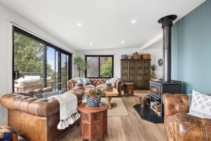 a living room with leather furniture and a fireplace at Omaroo in Wye River