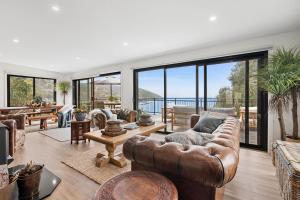 a living room with leather furniture and large windows at Omaroo in Wye River