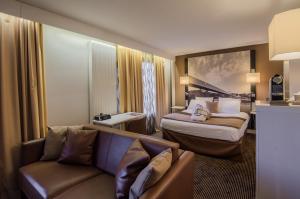 a hotel room with two beds and a couch at Mercure Cergy Pontoise Centre in Cergy