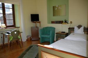a bedroom with a bed and a chair and a television at Hotel Sarbacher in Gernsbach
