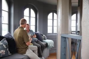 two people sitting on a couch in a living room at Ystads Gamla Vattentorn in Ystad
