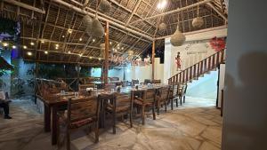 a dining room with a long table and chairs at Peace And Color Limited Guest House in Nungwi