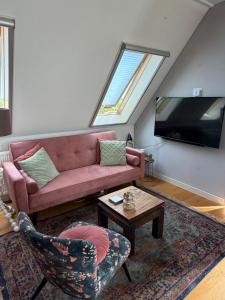 a living room with a pink couch and a tv at Complete studio de Stopplaats dichtbij Hoorn en Alkmaar in Zuidermeer