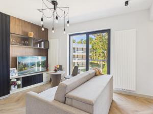 a living room with a couch and a tv at Shellter Resort Apartment by Solarento in Rogowo