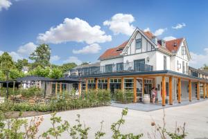 a large white house with large windows and a courtyard at Romantik Badhotel Renesse in Renesse