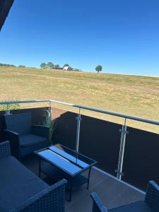 a balcony with chairs and a table and a field at Oak Wood Ranch Guest Apartment in Marsberg
