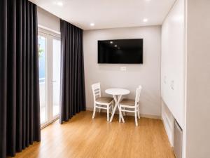 a dining room with a table and chairs and a tv at LUNA Hotel in Ho Chi Minh City