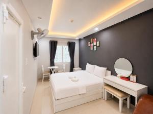 a bedroom with a white bed and a desk at LUNA Hotel in Ho Chi Minh City