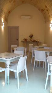 a dining room with white tables and white chairs at Kaleidos Guest House in Galatina