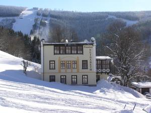 un edificio sobre una colina nevada en la nieve en Elisabeth Pension, en Špindlerův Mlýn