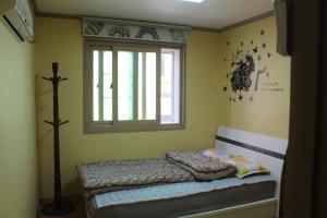 um pequeno quarto com uma cama e uma janela em Dadam Guesthouse em Yeosu