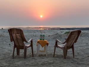 two chairs and a table with two candles on the beach at SaffronStays Salt Rim on the Beach, Korlai in Christpāda