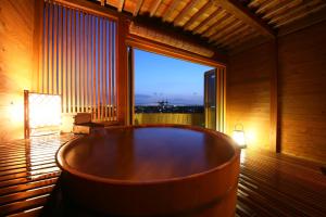 君津市にある旅館かわな -Ryokan Kawana-の大きな窓のある客室で、大きな木製のバスタブが備わります。