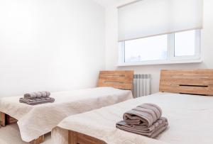 two beds in a white room with towels on them at Marja Apartment in Põltsamaa