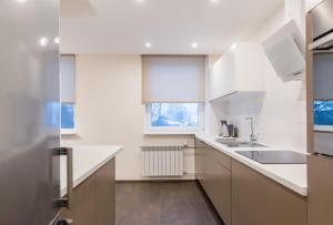 uma cozinha com armários brancos, um lavatório e uma janela em Marja Apartment em Põltsamaa