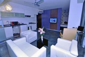 a living room with white furniture and a kitchen at Contemporary Heights Hotel and Apartments in Dhaka