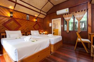 two beds in a room with wooden walls at Palm Leaf Resort Koh Tao in Ko Tao