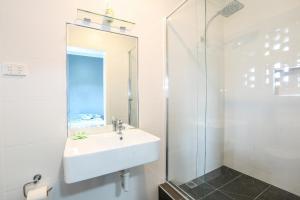 a bathroom with a shower, sink, and mirror at The Union Club Hotel in Colac