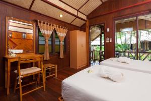 a bedroom with two beds and a desk and windows at Palm Leaf Resort Koh Tao in Ko Tao