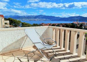 a chair sitting on a balcony overlooking the water at Panorama Postira Apartments in Postira