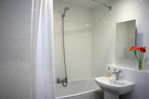 een witte badkamer met een wastafel, een bad en een douche bij Parc y Bryn Serviced Apartments in Aberystwyth +45 foto's