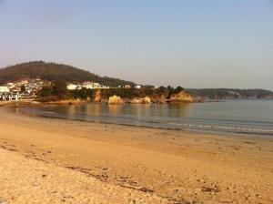 una playa de arena con una ciudad en el fondo en As Areas II, en Viveiro