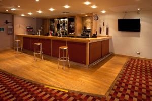 a bar with stools and a television in a room at Britannia Hotel Bolton in Bolton +27 photos